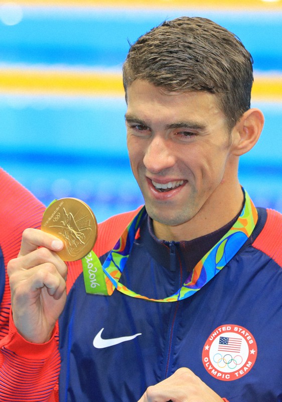 リオデジャネイロ五輪・競泳男子400メートルメドレーリレーの表彰式の後、目に涙を浮かべ金メダルを掲げるマイケル・フェルプス=リオデジャネイロの五輪水泳競技場で2016年8月14日、梅村直承撮影