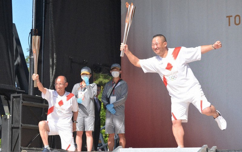 トーチキスの後、ポーズを取る県内最高齢ランナーの小森正幸さん(左)ら=石川県七尾市和倉町ひばり1の和倉温泉湯っ足りパークで、阿部弘賢撮影