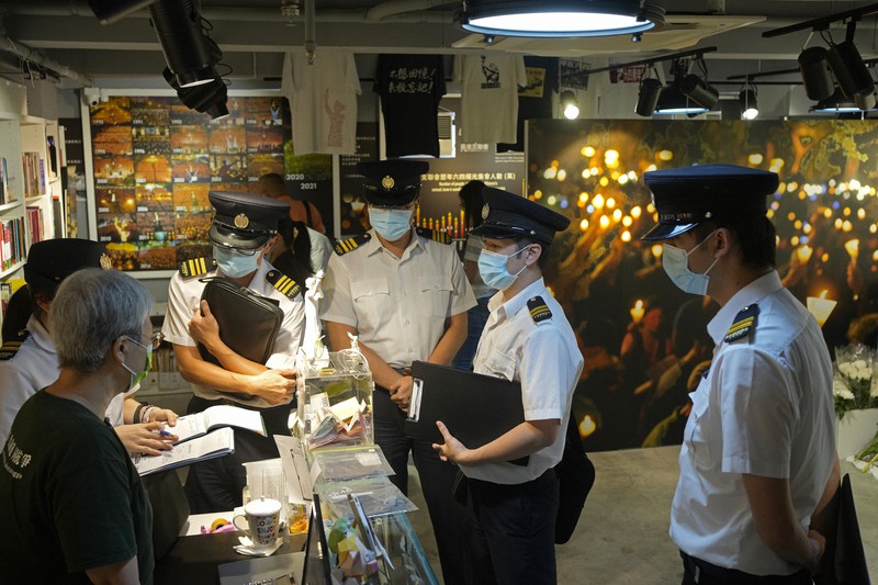 天安門事件の記念館の従業員(左)に質問する香港当局の職員たち=香港の同記念館で2021年6月1日、AP