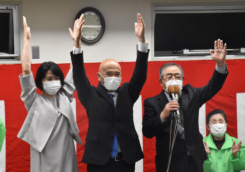 当選確実の一報を受けて笑顔でバンザイをする武久顕也氏(中央)=岡山県瀬戸内市邑久町豊原で2021年6日午後8時18分、戸田紗友莉撮影