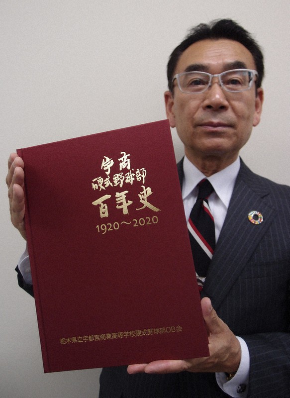 「宇商硬式野球部百年史」を持つOB会事務局長の平本光彦さん=宇都宮市の毎日新聞宇都宮支局で