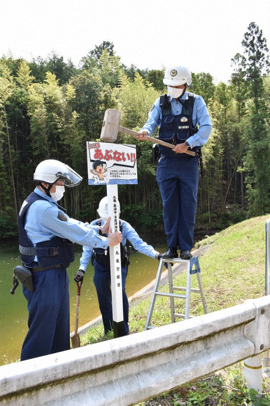 2021年5月に死亡事故が発生したため池に注意喚起の看板を設置する駐在所の警察官=香川県丸亀市綾歌町で、喜田奈那撮影