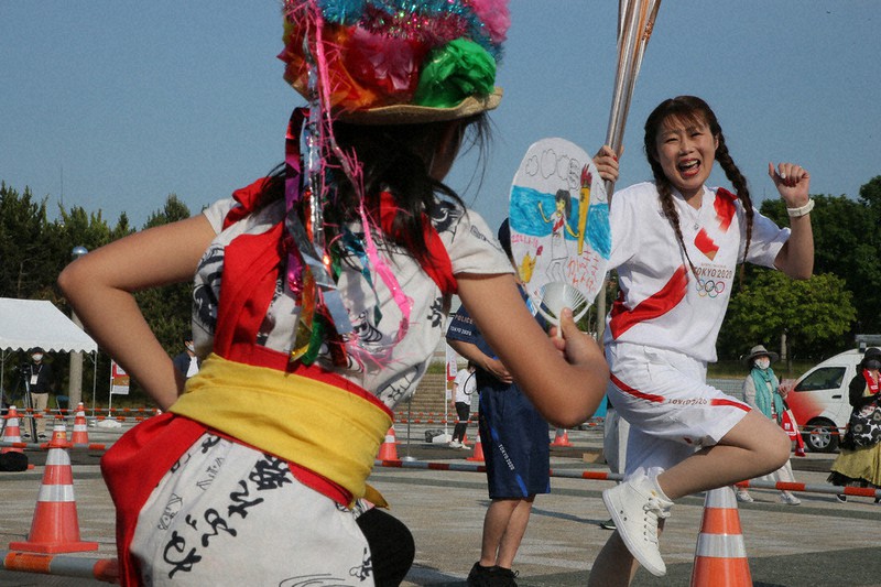東京オリンピック聖火のトーチを手に、青森ねぶた祭りのハネトの衣装をまとった子どもと一緒に跳ねる聖火ランナー=青森市で2021年6月10日午後4時9分、和田大典撮影