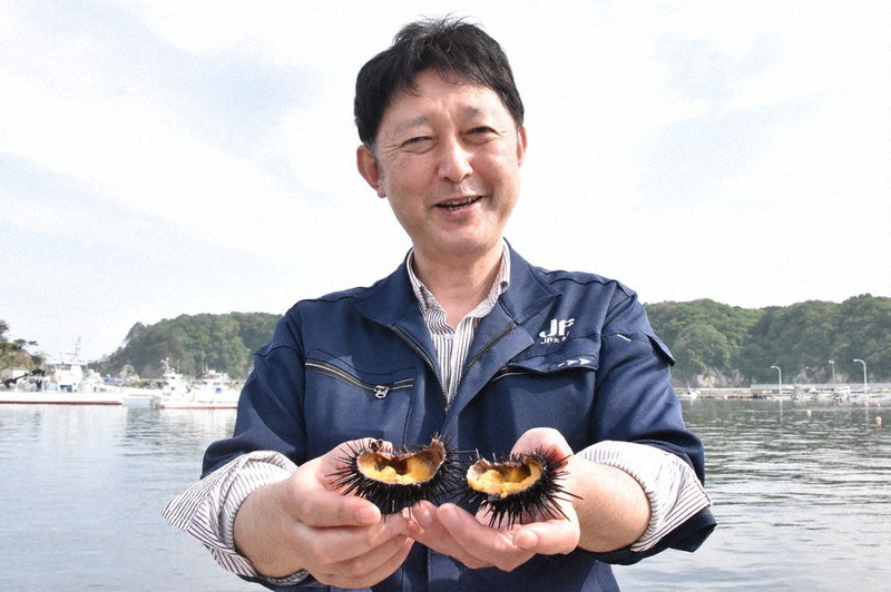 身の詰まった養殖ウニを手に、笑顔を見せる田老町漁協の畠山昌彦さん=岩手県宮古市田老で5月