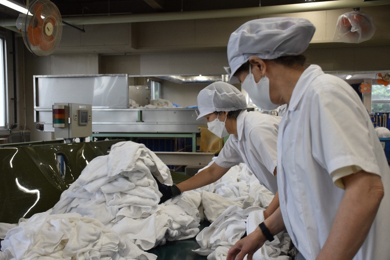ホテルから回収したタオルを仕分ける従業員=神奈川県厚木市の「テーオーリネンサプライ」厚木工場で2021年5月17日、町野幸撮影