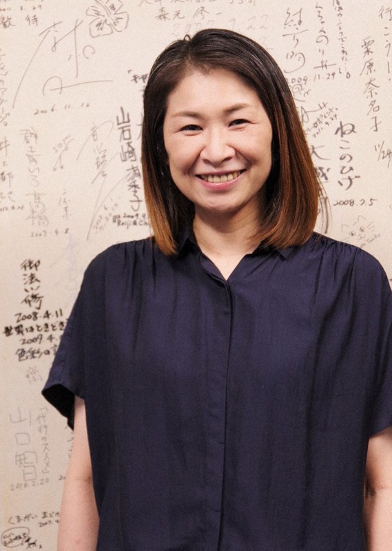 監督や俳優らのサインが書かれたボードをバックに笑顔を見せる志尾睦子さん=群馬県高崎市で2021年6月9日、佐藤伸撮影