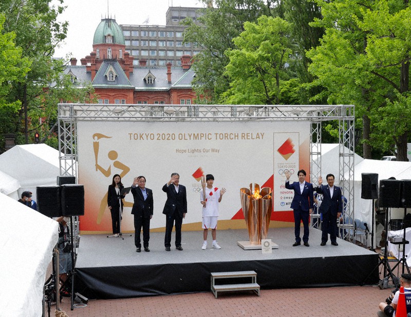 無観客で行われた点火セレモニー。聖火皿に火をともした湯川総夢さん(右から3人目)らが報道陣に向け手を振った=札幌市中央区で2021年6月14日、貝塚太一撮影
