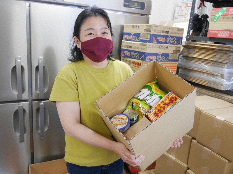 新型コロナで生活に困っている人に送る食料品入りの段ボール箱「応援ボックス」を抱えるNPO法人「西成チャイルド・ケア・センター」の川辺康子代表理事=大阪市西成区で2021年6月11日午後3時34分、野口由紀撮影