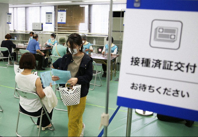 新型コロナウイルスワクチン接種の対象年齢が引き下げられた自衛隊大規模接種センターで、接種を終えて「接種済証」の手続きをする人たち=東京都千代田区の大手町合同庁舎3号館で17日午前11時59分、小出洋平撮影
