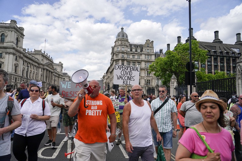英国のイングランドで新型コロナウイルスの感染拡大を受け、社会規制の全面解除が延期されたことに抗議する人たち=ロンドンで2021年6月14日、AP