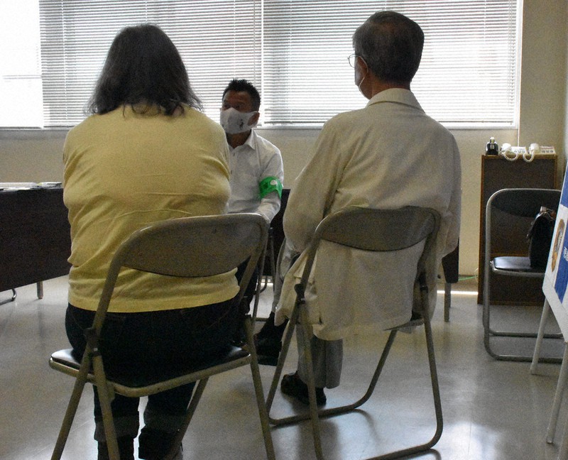 還付金詐欺の被害に遭いかけた体験を可児署員(中央)に説明する可児市の60代女性(左)と70代の夫=岐阜県警可児署で