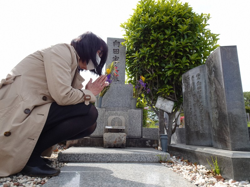 東京・多磨霊園にある向田邦子さんの墓前で手を合わせる長江曜子・聖徳大教授。右手に森繁久弥さんの言葉を刻んだ墓標がある