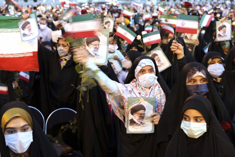 イラン大統領選で初当選したエブラヒム・ライシ司法府代表の絵を掲げ、祝う支持者ら=テヘランで19日、AP