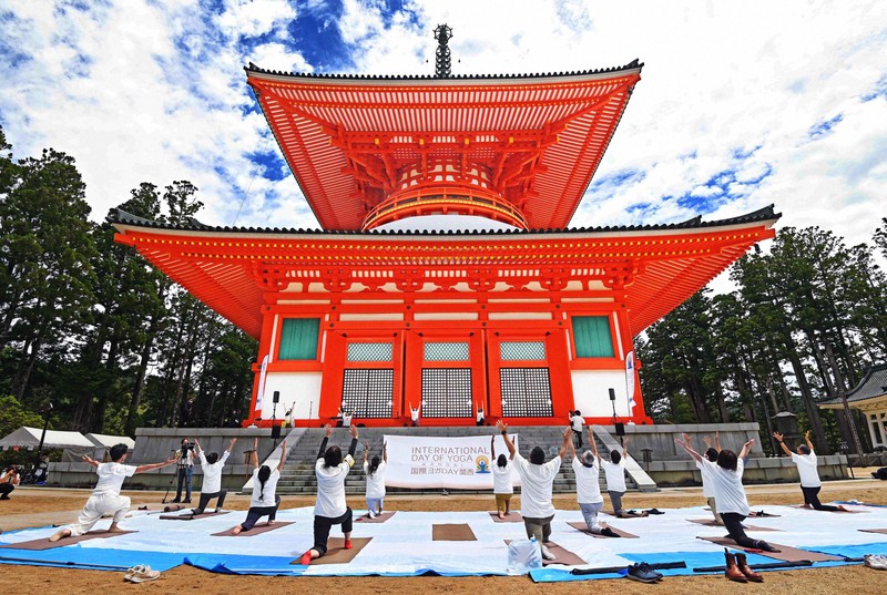 「国際ヨガの日」にちなんで行われた「1000人ヨガ」のオンライン配信で、壇上伽藍の根本大塔前でヨガを行う参加者たち=和歌山県高野町で2021年6月20日、山崎一輝撮影