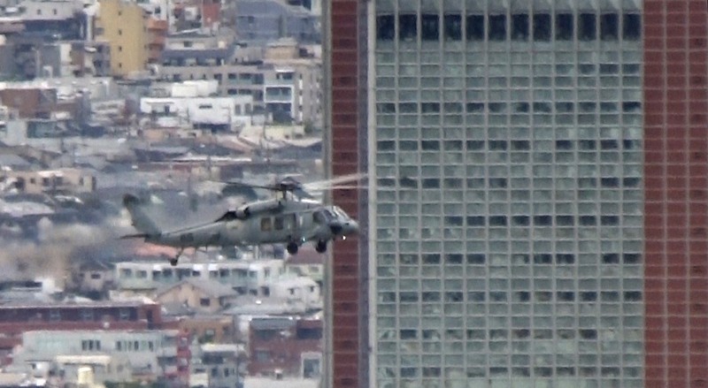 東京都世田谷区太子堂の「キャロットタワー」(高さ124メートル)手前を通過する米海軍ヘリ「シーホーク」=2020年12月14日午後1時25分ごろ、大場弘行撮影(写真は動画から)