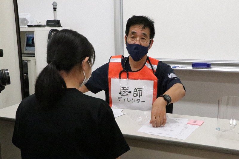 ワクチン接種を前に学生を問診する安東由喜雄学長(奥)=長崎県佐世保市の長崎国際大で2021年6月21日午後1時、綿貫洋撮影