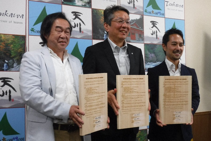 調印後、木製の協定書を手に笑顔を見せる車谷村長(中央)と水谷事務局長(右)ら=天川村役場で、高田房二郎撮影