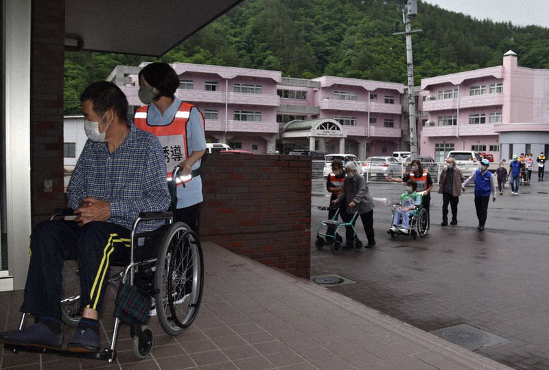 介護老人保健施設「ふれんどりー岩泉」(奥)から岩泉HD乳業事業部への避難訓練に参加する通所利用者ら=岩手県岩泉町乙茂で2021年6月24日、中尾卓英撮影