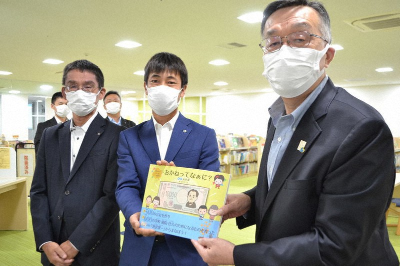 日本商工会議所青年部が発行した絵本を持つ梅本達矢会長(中央)と山本雅弘教育長(右)=京都府宮津市立図書館で、松野和生撮影