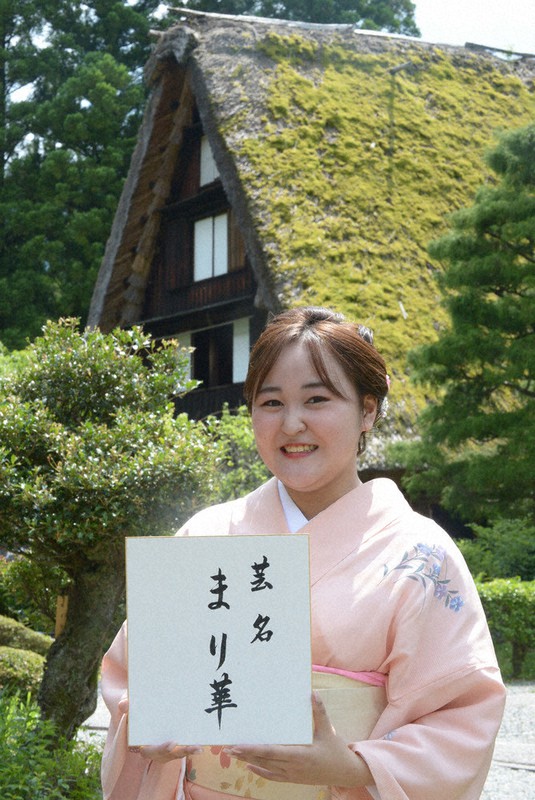 合掌造り民家をバックに舞妓の芸名「まり華」を披露する竹元磨理華さん=岐阜県下呂市森の下呂温泉合掌村で2021年6月25日、大竹禎之撮影