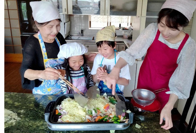 祖母、母、子どもの3世代で調理する家族