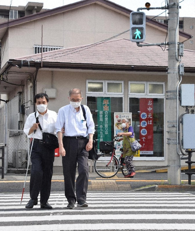 横断歩道を渡る群馬県視覚障害者福祉協会会長の茂木勤さん(左)。同伴しているのは同協会事務局長の金井雅之さん=前橋市六供町で2021年6月11日午後2時54分、菊池陽南子撮影
