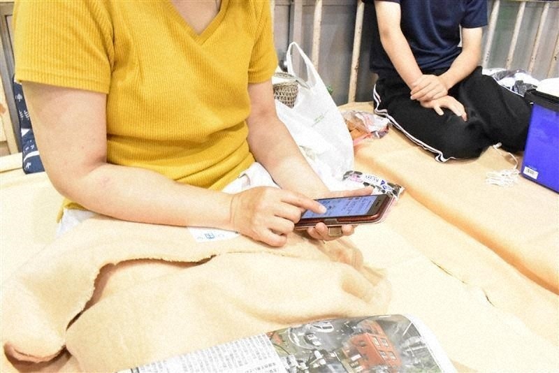 静岡県の防災サイトをスマートフォンでチェックする安藤優子さん(左)と長男の彬希さん=静岡県熱海市桃山町で、太田圭介撮影