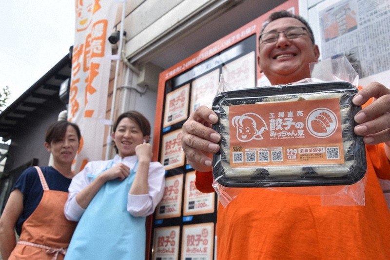 自動販売機の前で復活させたギョーザを紹介する鈴木健正さん(右)。左は関根美智子さん=群馬県高崎市並榎町で021年6月26日、菊池陽南子撮影