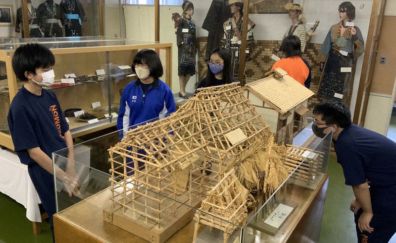 校内にある郷土資料室で、アイヌ民族伝統の住居「チセ」などを観賞する北海道旭川市立北門中の郷土史研究部員ら=松本賢尚教諭提供