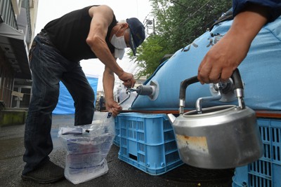 土石流の被災地周辺では断水が続き、給水所で水をくむ近くに住む男性＝静岡県熱海市伊豆山で２０２１年７月９日午前８時５分、手塚耕一郎撮影