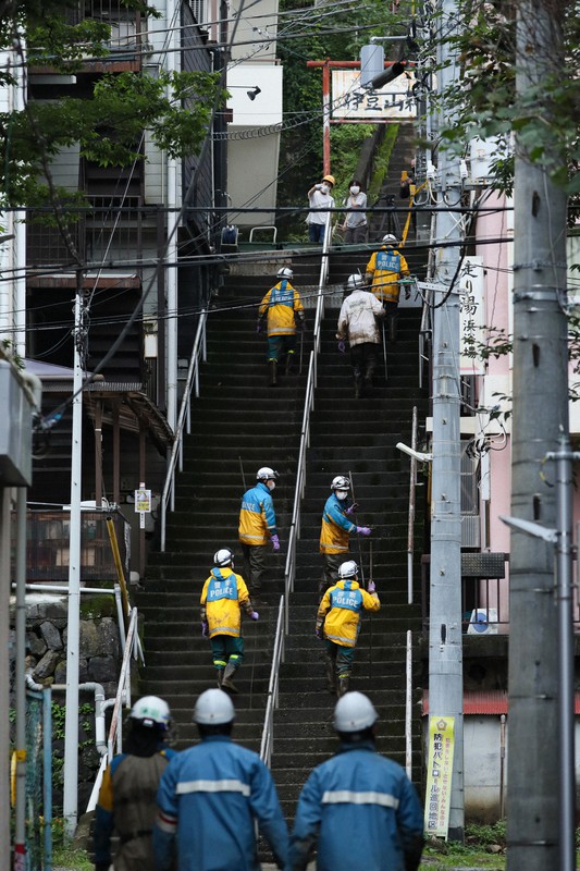 階段が多い伊豆山地区でいまだ泥が残るエリアを捜索して回る静岡県警の警察官ら=静岡県熱海市伊豆山で2021年7月9日午後3時5分、吉田航太撮影