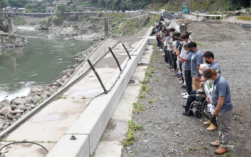 九州豪雨から1年の4日、球磨川沿いで黙とうする住民たち=熊本県球磨村で、平川義之撮影