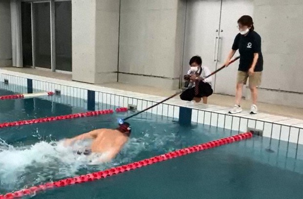 釣りざおで自作した棒でタッピングをする風間みどりさん(右)=本人提供