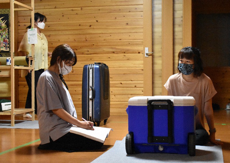 「座卓」を囲んで会話する次女役の栗原一美さん(右)と長女役の小川裕子さん(左)。後から会話に加わる母親役の中村ひろみさん(後方)=群馬県太田市大原町で2021年7月1日午後8時42分、鈴木敦子撮影