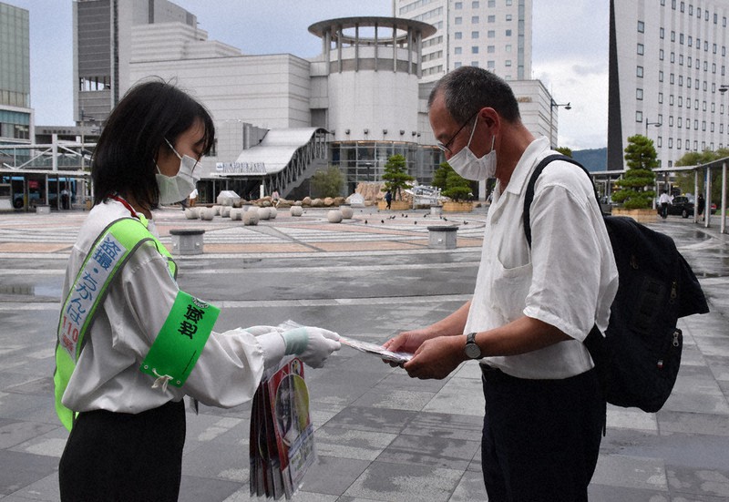 JR高松駅前でうちわなどを配る穴吹デザインカレッジの学生(左)=高松市浜ノ町で、喜田奈那撮影