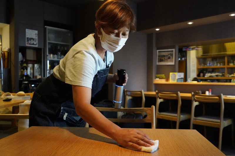 休業中の店内で除菌スプレーを使ってテーブルを拭く「旬菜鮪処 英」の店主、大野薫さん=東京都文京区で2021年7月19日、渡部直樹撮影