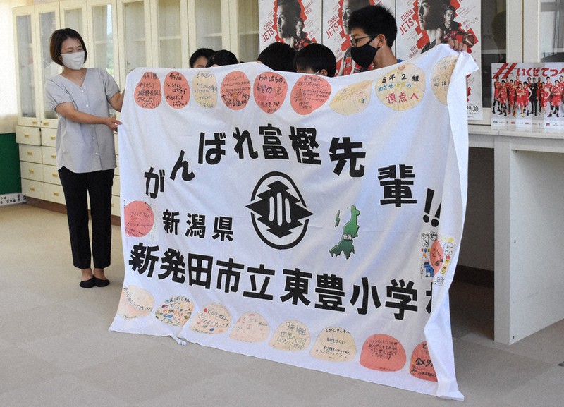 富樫選手の母恵子さん(左端)に激励旗を贈呈する児童たち=新潟県新発田市の東豊小学校で2021年7月19日、池田真由香撮影