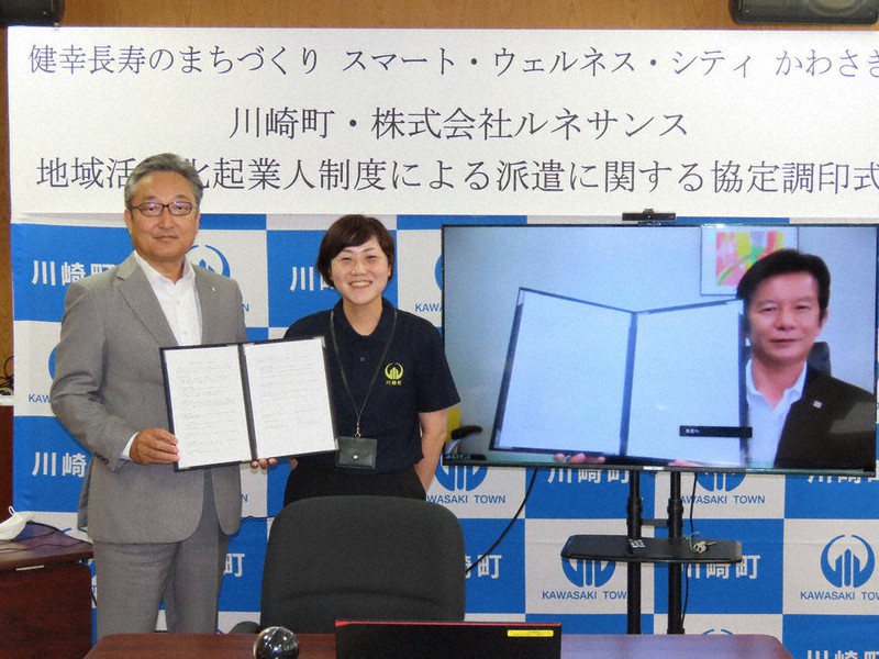 協定書を手にする(左から)原口町長、小林さん、リモート参加の岡本社長