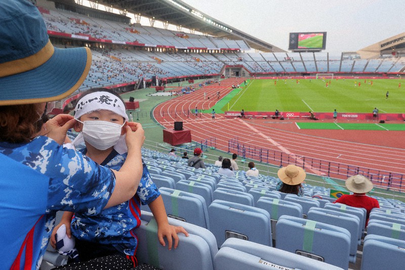 有観客で開催された東京オリンピックのサッカーの試合中、子どものマスクを着け直す母親=宮城県利府町のキューアンドエースタジアムみやぎで2021年7月21日、和田大典撮影