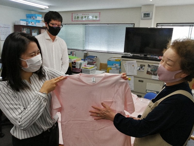 環境に配慮し、過剰在庫となっていた新品のTシャツを介護事業所の制服に提案した一柳翠さん(左)=ネクストエージ提供