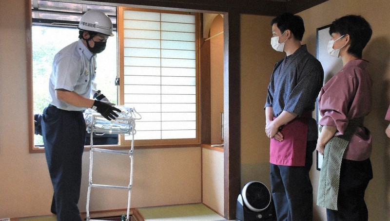 避難器具の使い方を消防署員(左)から教わる「京の宿 北海館 お花坊」の従業員ら=京都市下京区で、添島香苗撮影