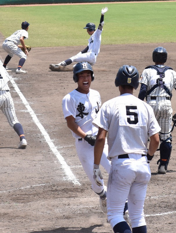 【東山-西城陽】三回表東山1死二、三塁、原(奥中央)の適時三塁打で生還し、笑顔を浮かべる二走の吉沢(手前中央)=京都市右京区のわかさスタジアム京都で、中島怜子撮影