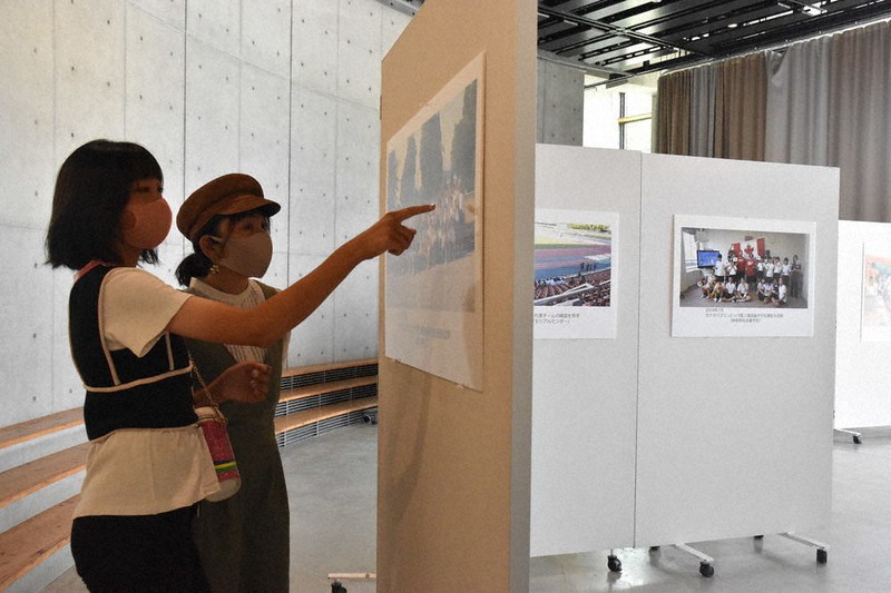「ホストタウン」となった3カ国の選手団と、岐阜市民が交流する様子が収められた写真を眺める来館者=岐阜市司町のみんなの森ぎふメディアコスモスで2021年7月23日、熊谷佐和子撮影