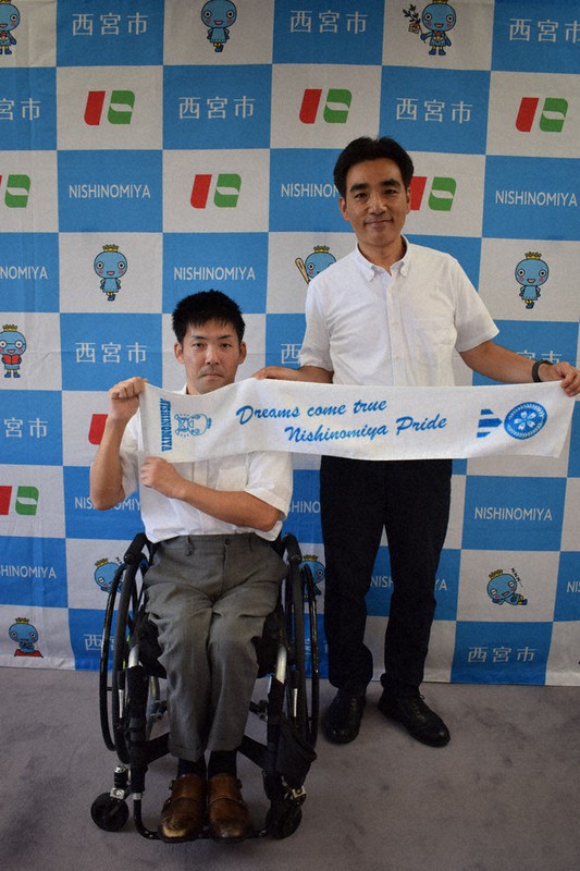 石井登志郎市長(右)から贈られたスポーツタオルを掲げるパラ陸上代表の大矢勇気選手=兵庫県西宮市六湛寺町の市役所本庁舎で、稲田佳代撮影