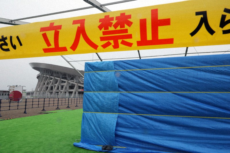 台風8号の接近により、五輪サッカー会場(奥)前に展示された東日本大震災からの復興などを紹介するパネルにかぶせられたシート=宮城県利府町で2021年7月27日午前9時37分、和田大典撮影