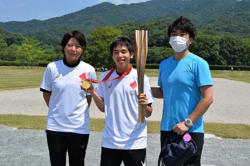 金メダルをかけ、トーチを持って藤本さん(左)と記念写真に納まる参加者