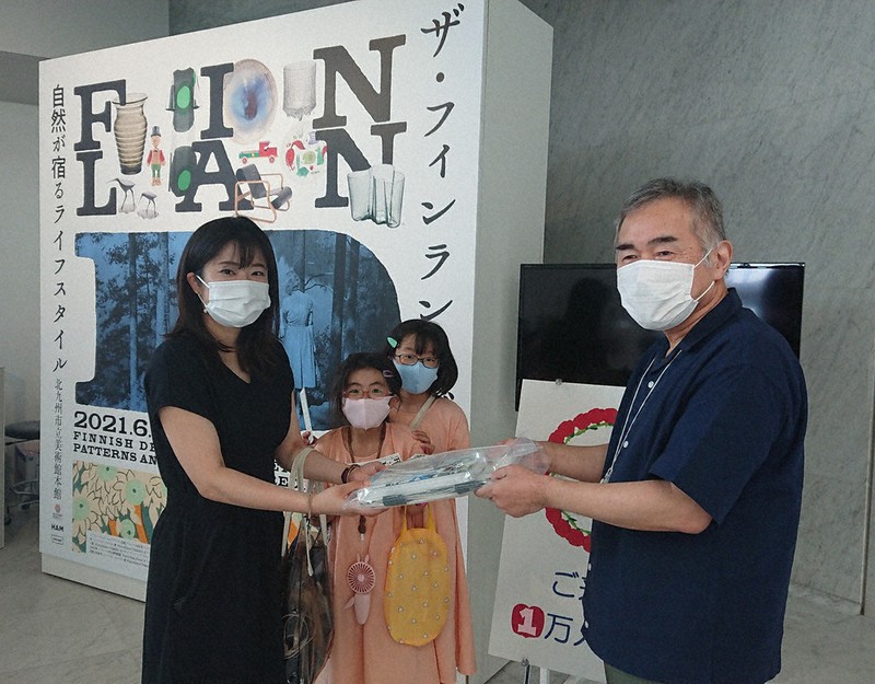 後小路館長(右)から入場1万人目の記念品を贈られる板岡さん(左端)