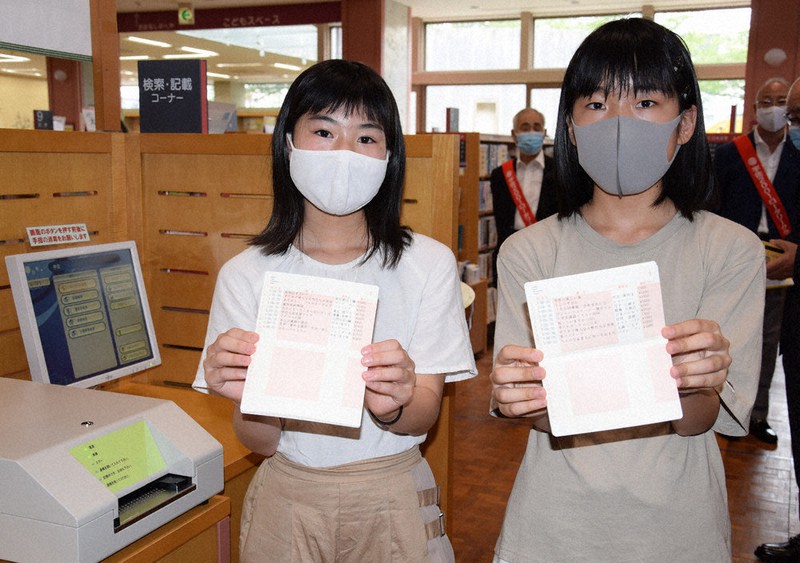 読書の通帳のデモ体験をした松田さん(右)と川浦さん。左は記帳機