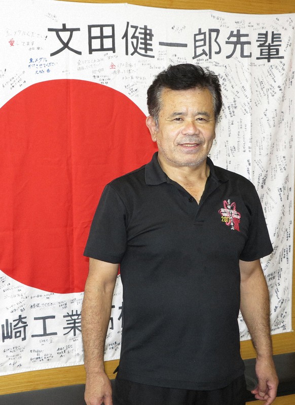 文田健一郎選手の健闘を祈る山梨県立韮崎工業高の後輩の寄せ書きの前に立つ父敏郎さん=同県韮崎市で2021年7月26日午後0時4分、山本悟撮影