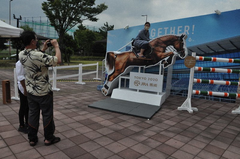 実物大の馬と東京五輪競技会場の馬事公苑を背景にした記念撮影スポットで、写真撮影する夫婦